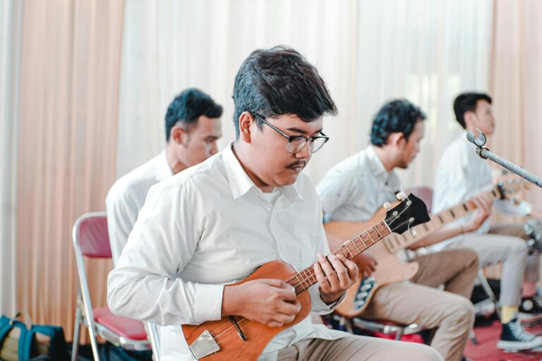 Group of young men playing ukuleles indoor, focusing on music session.